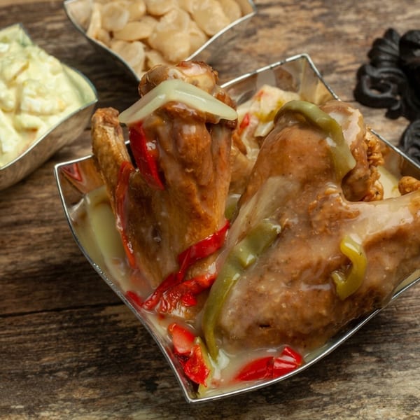 Chicken wings with red and green peppers in a creamy sauce, with sides of white beans and dip.
